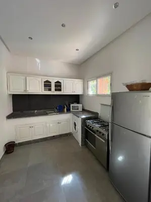 a kitchen with white cabinets and a stainless steel refrigerator at Riad-style triplex in secure residence in Marrakech