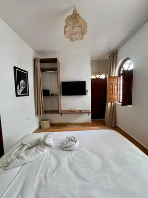 a large white bed in a bedroom with a television at riad les cinq terres in Marrakech