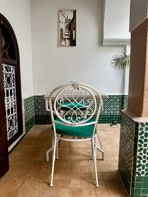 a chair sitting next to a table in a room at riad les cinq terres in Marrakech