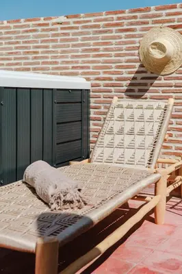 a wooden bench sitting next to a brick wall at Riad Les Sultanes Havre de paix avec jacuzzi prive in Marrakech