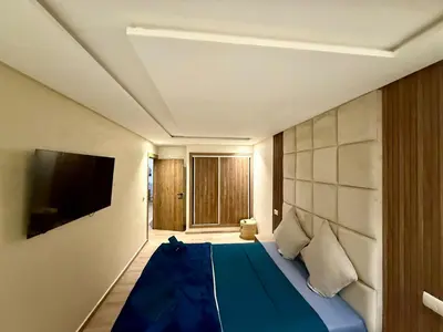 a bedroom with a blue bed and a flat screen tv at Duplex chic et lumineux avec piscine proche centre in Marrakech