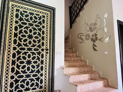 a door with a stenciled design next to a staircase at Villa Dar Ouladi - Marrakech - Pool & Rooftop in Marrakech