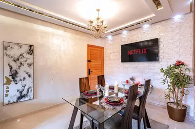 a dining room with a table and a tv on a brick wall at Emeraude - Confort et parking privé in Marrakech