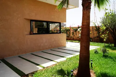 a house with a palm tree next to a sidewalk at Villa Lily in Tameslouht