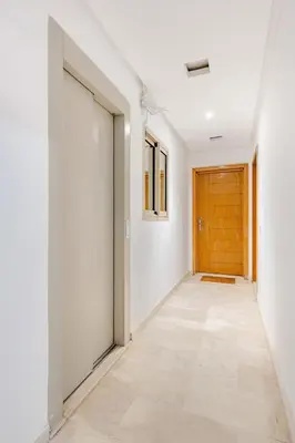 a hallway with white walls and a wooden door at Propre et bien situé avec parking sous-sol etWi-Fi in Marrakech