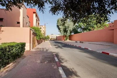 an empty street with trees and buildings on the side at Propre et bien situé avec parking sous-sol etWi-Fi in Marrakech