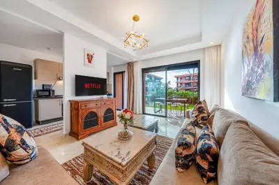 a living room with a couch and a table at Appartement moderne et spacieux avec terrasse et piscine au Noria Golf in Marrakech