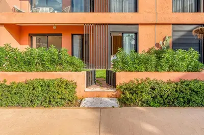 an orange building with bushes in front of it at Appartement moderne et spacieux avec terrasse et piscine au Noria Golf in Marrakech