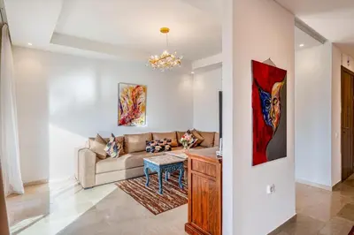 a living room with a couch and a table at Appartement moderne et spacieux avec terrasse et piscine au Noria Golf in Marrakech