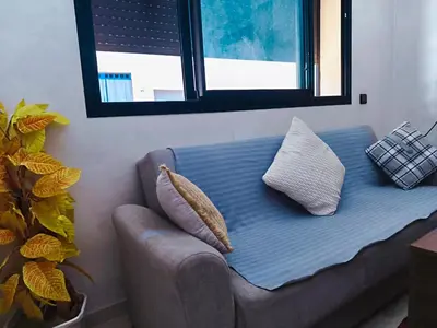 a couch with pillows sitting in a room with a window at Cocoon Apartment & Pool ctm aeropot train station in Marrakech