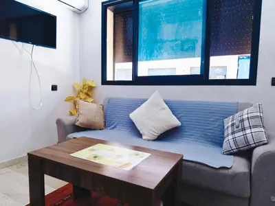 a living room with a blue couch and a table at Cocoon Apartment & Pool ctm aeropot train station in Marrakech