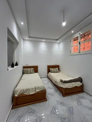two twin beds in a room with marble floors at Stylish Moroccan Apartment in Marrakech