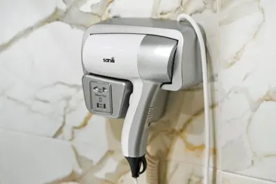 a hair dryer hanging on a wall in a bathroom at Charmant appartement avec terrasse au cœur de Marrakech in Marrakech