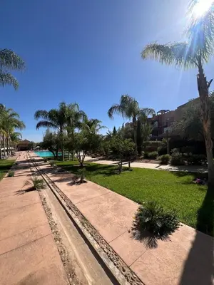 a walkway with palm trees and a beach at Appartement de charme au Vizir Resort in Dar Caïd Layadi
