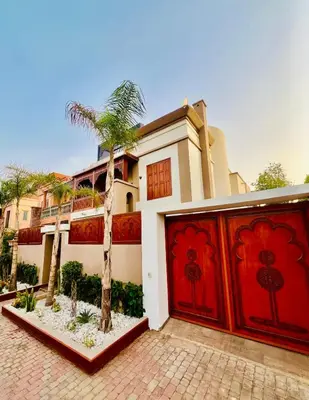 a house with a palm tree in front of a garage at Dar Jacaranda in Marrakech