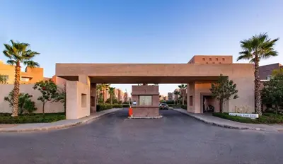 a building with a parking lot with palm trees at Marrakech prestigia in Marrakech