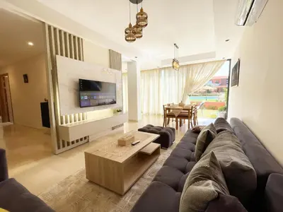 a living room with a large couch and a table at Ground floor 2 elegant bedrooms with direct pool access in Marrakech