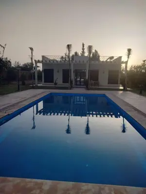 a blue swimming pool with a house in the background at Villa Elbidaoui in Marrakech