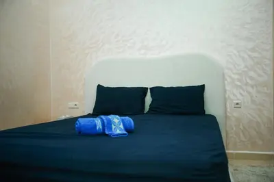 a bed with a blue blanket and two pillows at New apartment rental in Marrakech