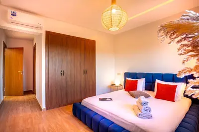 a bedroom with a blue bed with red pillows at Luxueux appartement piscine coralia in Marrakech