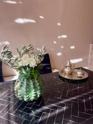 a vase filled with flowers on a table at Riad Muvira in Marrakech