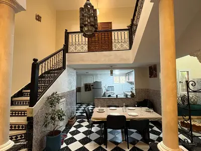 a dining room with a table and a staircase at Riad Flouris in marrakech in Marrakech