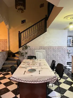 a dining room with a table with chairs and a staircase at Riad Flouris in marrakech in Marrakech