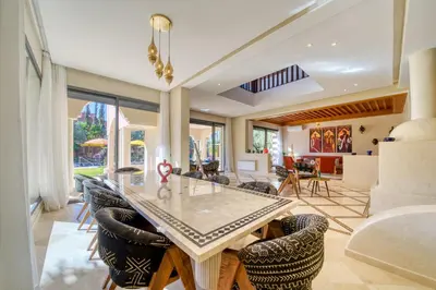a dining room with a glass table and chairs at Villa Juzyan Piscine-Jacuzzi-Pataugeoire-Pétanque in Marrakech