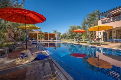 a swimming pool with umbrellas and chairs next to it at Villa Juzyan Piscine-Jacuzzi-Pataugeoire-Pétanque in Marrakech