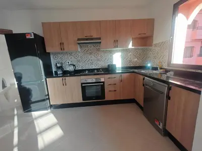 a kitchen with wooden cabinets and stainless steel appliances at Elegant Apartment with King-Size Bed, Premium Amenities, 5 Pools & Free Parking in Marrakech