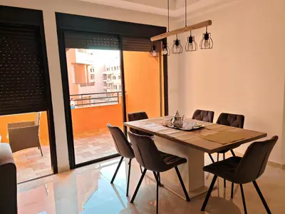 a dining room with a wooden table and chairs at Elegant Apartment with King-Size Bed, Premium Amenities, 5 Pools & Free Parking in Marrakech