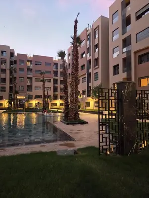 a courtyard of a building with a pool and palm trees at Jnane el Ali Gueliz in Marrakech
