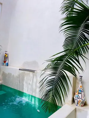 a palm tree sitting next to a swimming pool at Riad Dar Amazonia in Marrakech