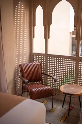 a chair and a table in a room with windows at Riad Dar Amazonia in Marrakech