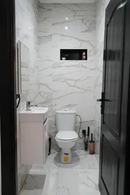 a white bathroom with a toilet and a tv on the wall at apartment in the center for an excellent stay in Marrakech