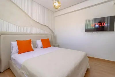 a bedroom with a white bed with two orange pillows at New Charming apartment with swimming pool in Marrakech