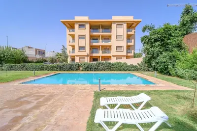 two white chairs sitting next to a swimming pool at New Charming apartment with swimming pool in Marrakech