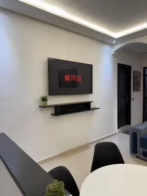 a tv on a wall in a room with chairs at Appartement chic près de Guéliz Calme & confort à Marrakech in Marrakech