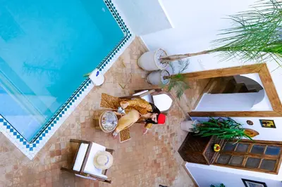 an overhead view of a woman laying on a floor next to a pool at Riad Zellige in Marrakech