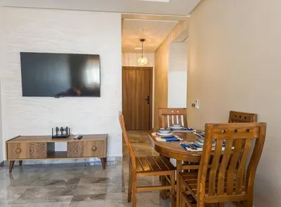 a dining room with a table and a television on the wall at Appartement Marrakech 2 Chambres De Luxe Orange in Marrakech