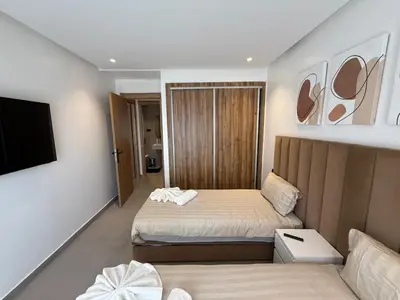 a small bedroom with a bed and a tv at T3 élégant 2ch piscine chauffée & fitness in Marrakech