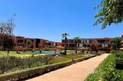 a walkway next to a park with a swimming pool at Cosy Apartment with Balcony and Pool in Noria Golf in Marrakech
