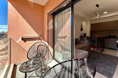 a balcony with two chairs and a living room at Cosy Apartment with Balcony and Pool in Noria Golf in Marrakech