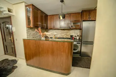 a kitchen with wooden cabinets and a refrigerator at Royal Pool Apartment Hivernage Marrakech in Marrakech