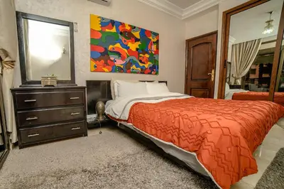 a bedroom with a bed and a dresser and a mirror at Royal Pool Apartment Hivernage Marrakech in Marrakech