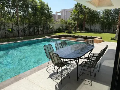 a table and chairs next to a swimming pool at Ayline house in Marrakech
