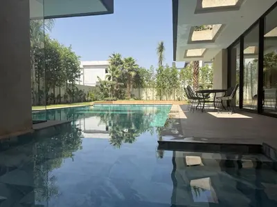 a swimming pool with a table and chairs in a house at Ayline house in Marrakech