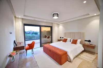 a bedroom with a large bed and a orange chair at Luxury villa with heated pool and Hamam in Marrakech