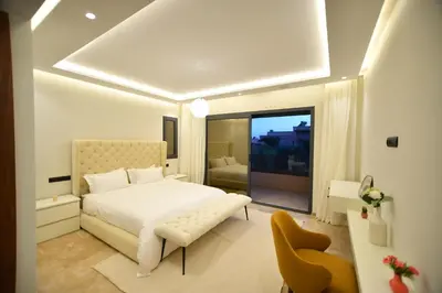 a bedroom with a white bed and a yellow chair at Luxury villa with heated pool and Hamam in Marrakech