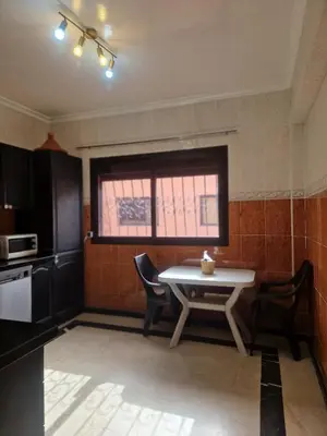 a kitchen with a table and chairs and a window at Appartement 2 chambres, piscine, vue palmeraie in Marrakech